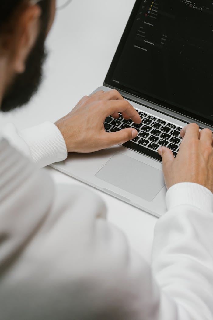 Offerings A male programmer intensely typing code on a laptop, showcasing modern technology and software development.